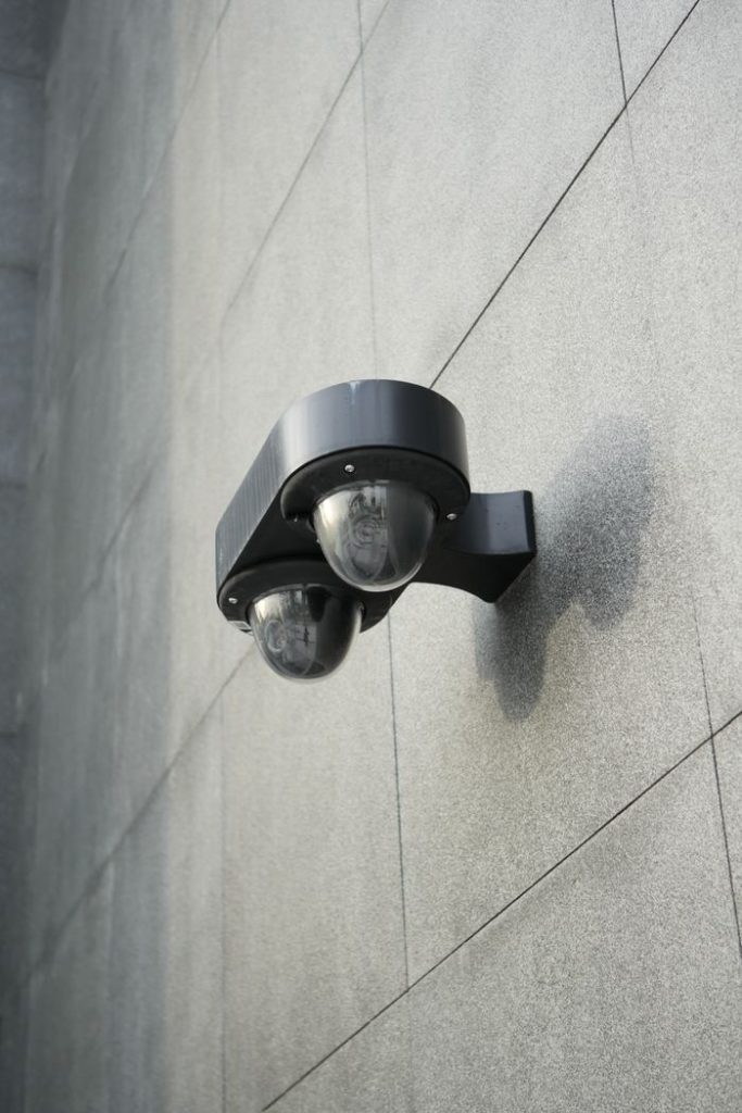 black-motion-sensor-on-gray-wall-13716995 A security camera mounted on a sleek gray concrete wall for monitoring
