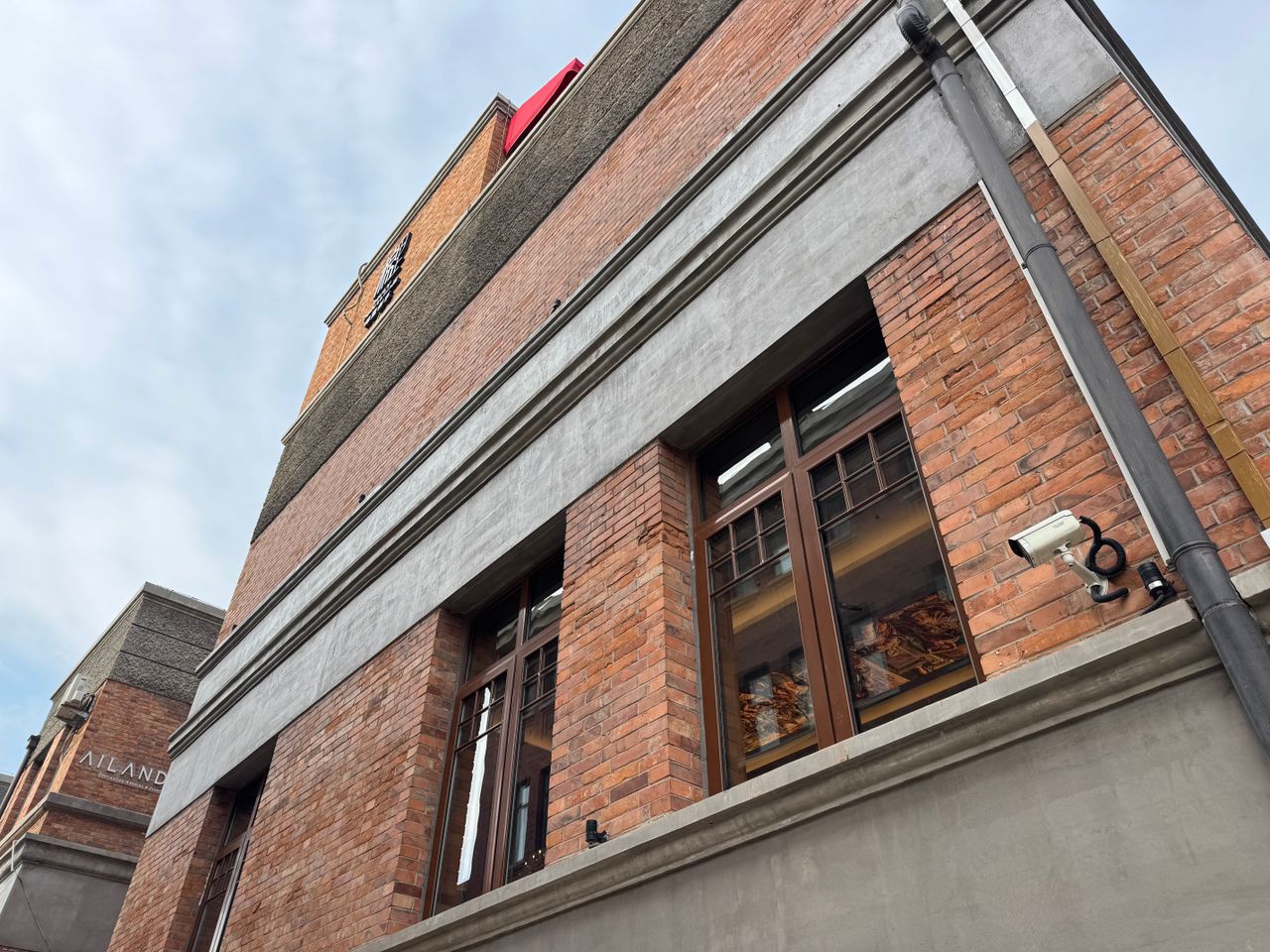 Low angle view of a red brick building facade with windows and a security camera.